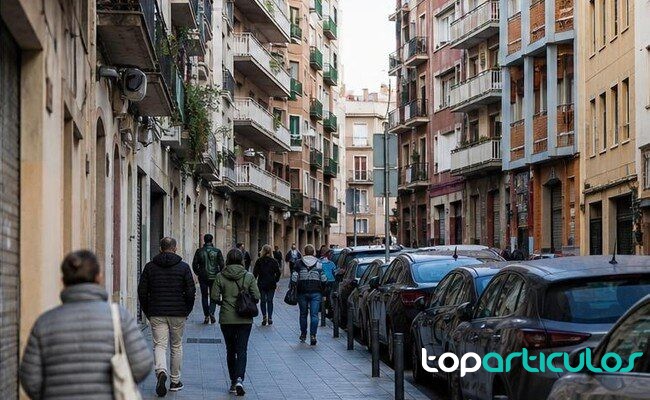 Presión residencial urbana Calle urbana española con edificios de viviendas y peatones