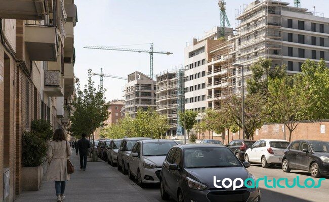 Vivienda pide limitar los pisos turísticos en zonas tensionadas tras el aviso del Banco de España Calle de una ciudad española con edificios de viviendas y obra residencial