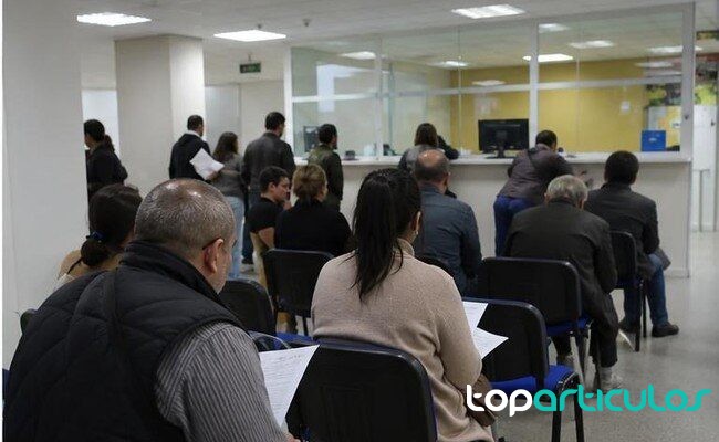 Acceso a vivienda y hogares Personas revisando documentos de vivienda en una oficina publica