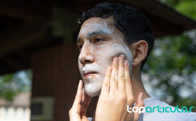 Aplicación uniforme de fotoprotector facial antes de salir persona aplicando protector solar en el rostro