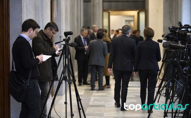 Cobertura informativa tras una reunión internacional de seguridad periodistas esperan declaraciones en un pasillo institucional