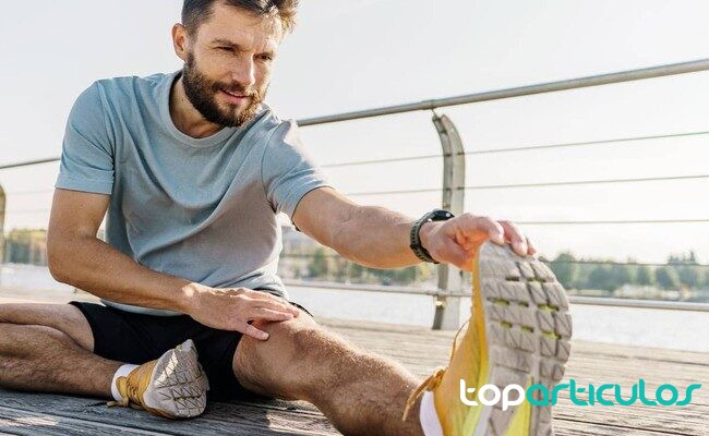 Recuperación activa tras una sesión combinada de fuerza y carrera deportista estirando después de entrenar